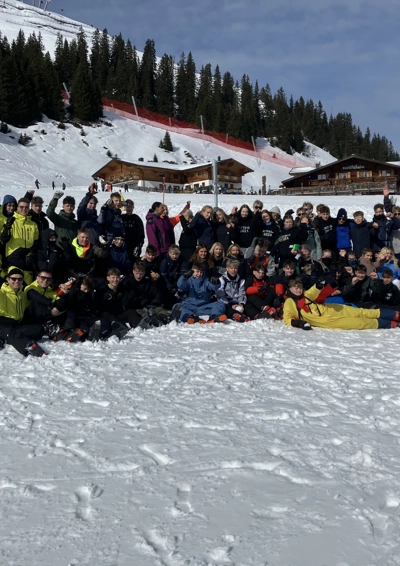 Masse unge der står på en ski bakke og smiler til kameraet